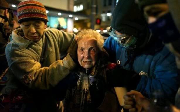 Seattle activist Dorli Rainey, 84 years on Gods green earth, survivor of Nazi occupied Germany, being helped to safety by two other protesters after she was directly sprayed with mace during an Occupy Seattle protest on Tuesday, November 15, 2011 at Westlake Park.
