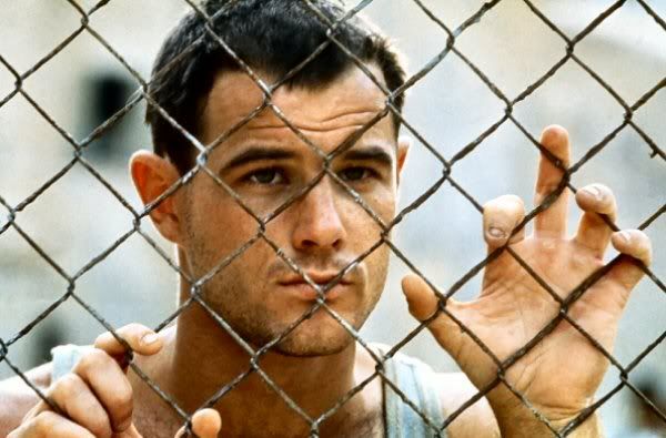 Brad Davis holding barb wire fencing in prison scene from Midnight Express